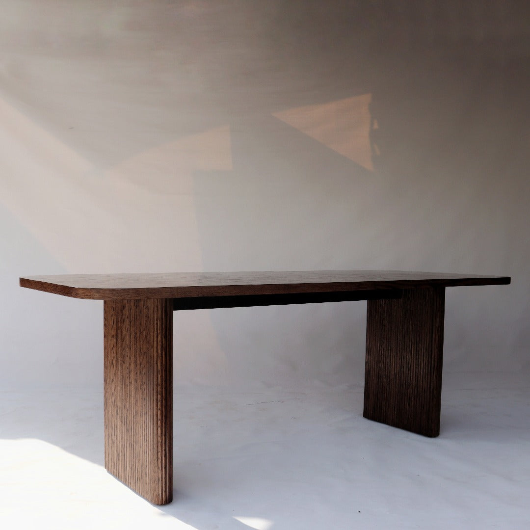 Exquisite dining table featuring sleek, fluted legs and rich red oak wood construction, adding elegance to any dining space.