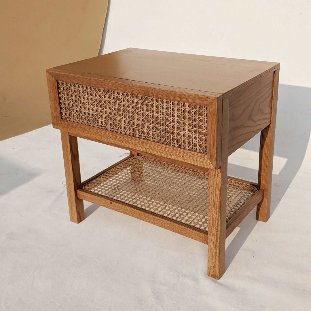A nightstand with a cane-woven drawer front, offering a stylish storage solution with a touch of natural texture. The woven cane detailing adds visual interest and warmth to the room, while the sleek design ensures functionality and versatility.