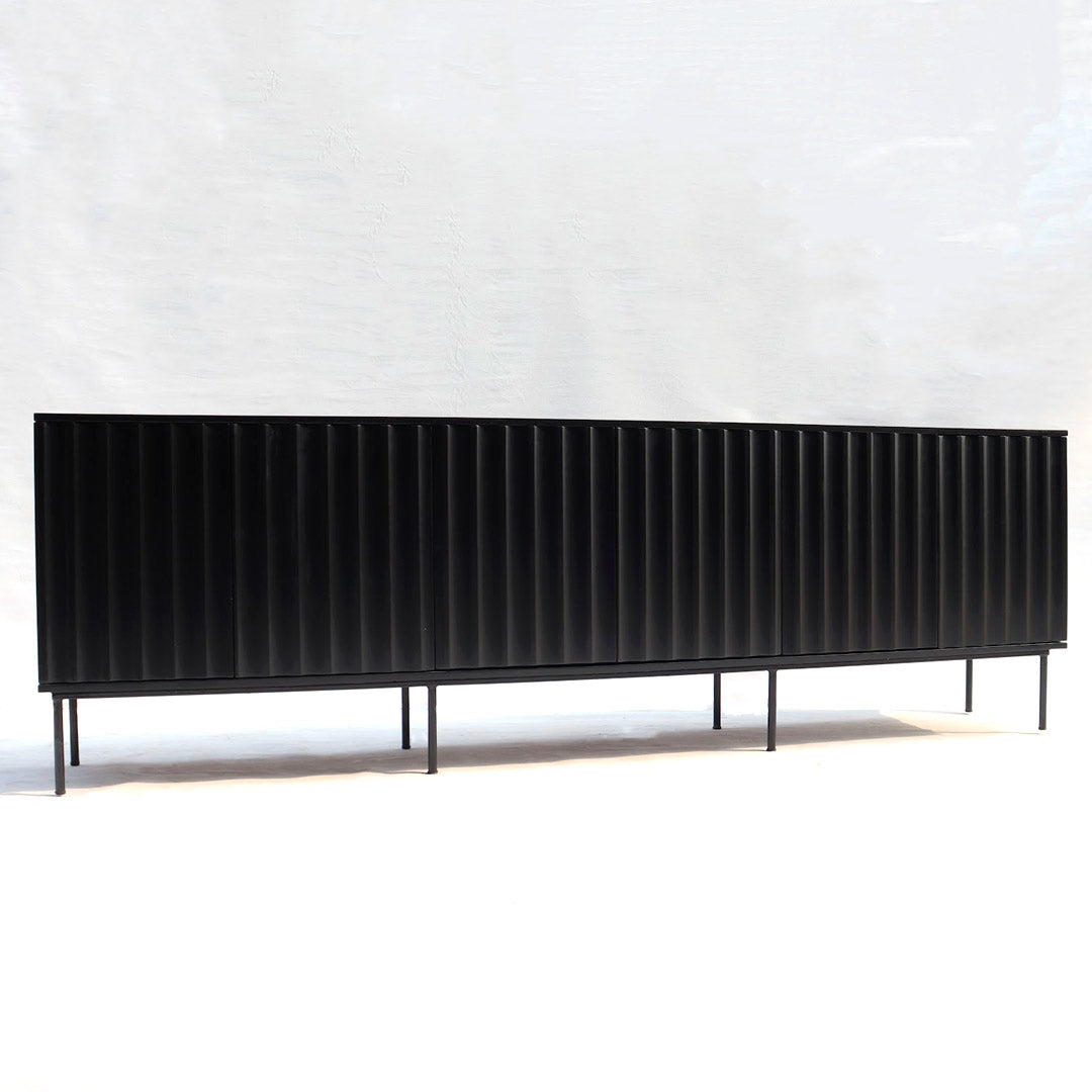 A fluted console, characterized by vertical grooves or channels along its surface. The fluted design adds texture and visual interest to the console, creating a stylish and sophisticated statement piece for any entryway or living space.