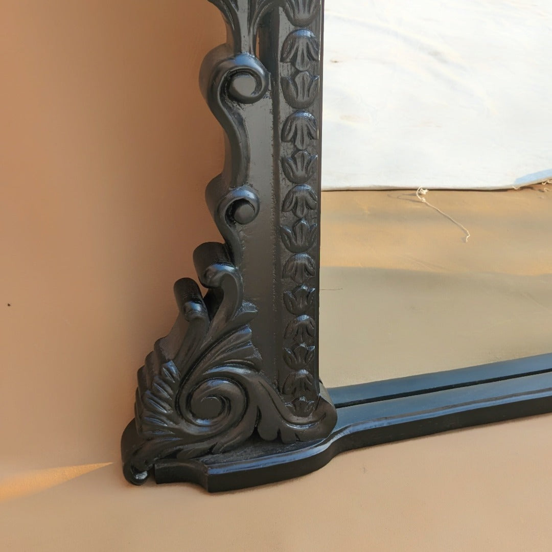 A handcrafted mirror from Anthropology, intricately carved with elaborate designs and motifs. Its artisanal beauty brings a touch of elegance and cultural richness to any space, reflecting light and enhancing the ambiance with its unique craftsmanship.