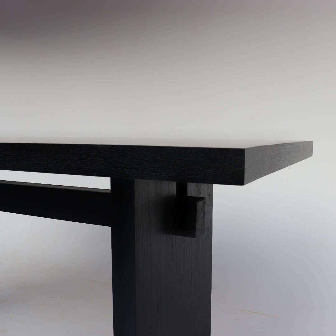 Robust dining table with a sturdy frame, crafted from Solid Red Oak and Red Oak Veneer, and finished in a matte black for a sleek and modern look.