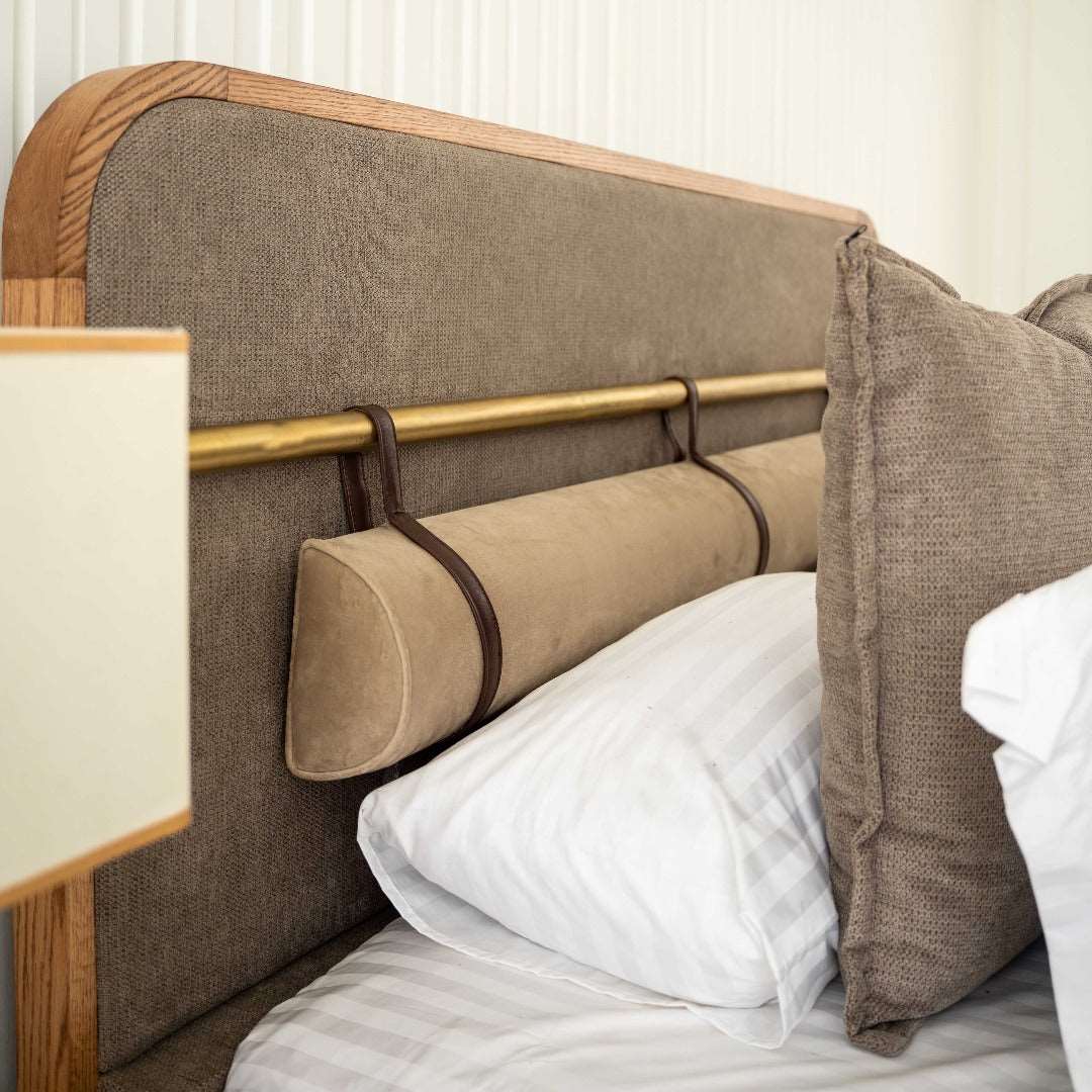 A luxurious bed with a rich red oak wood frame, accented by brass and faux leather buckle detailing. Its elegant design exudes opulence, combining natural textures with metallic accents for a sophisticated statement piece in any bedroom.