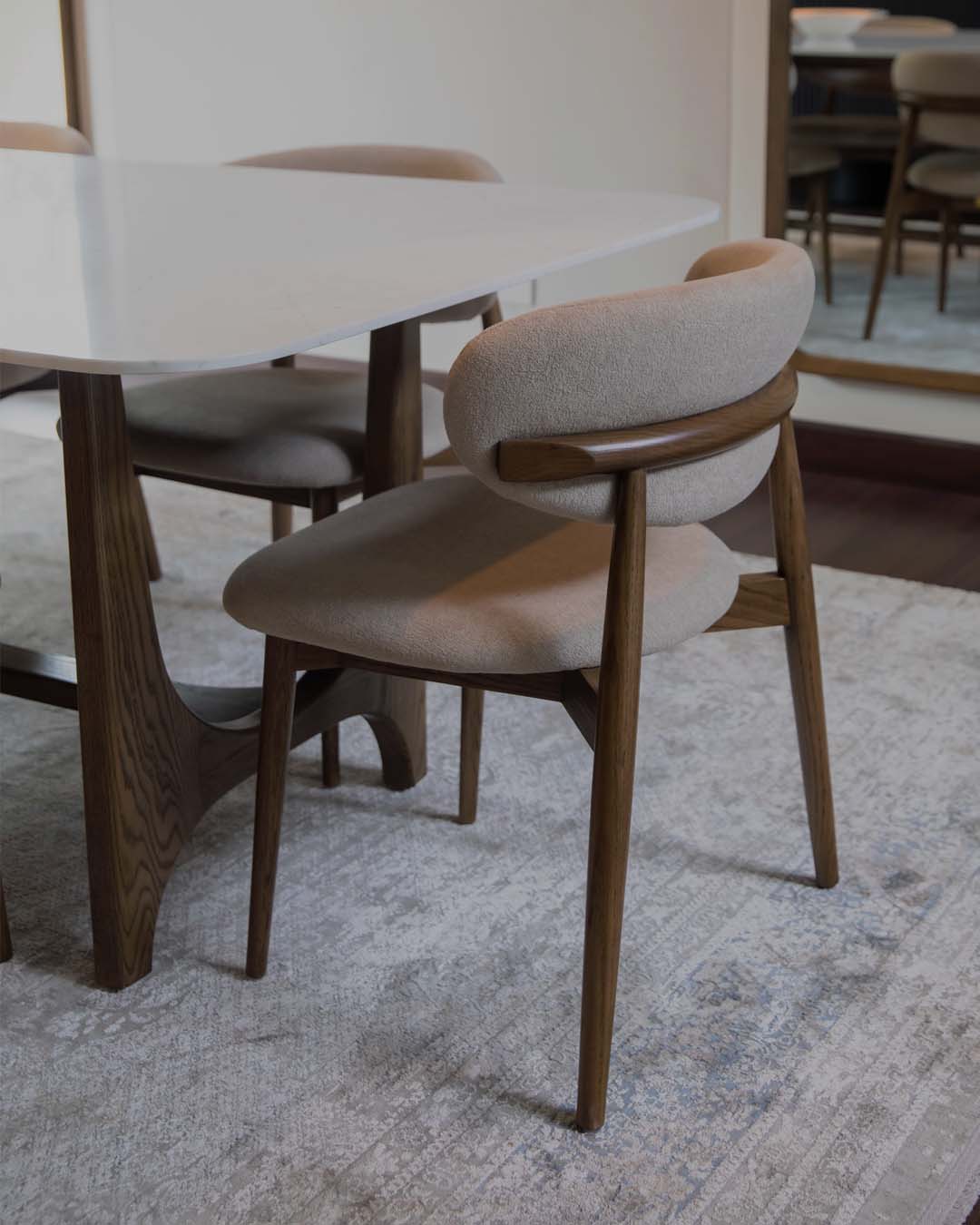 Dining chair with wooden frame and beige cushion on a textured rug