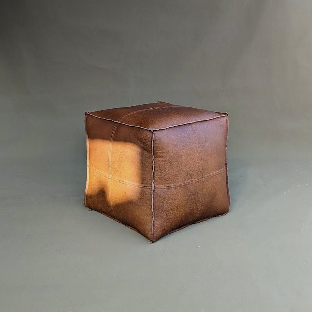 A square pouf made with leather, offering comfortable seating and stylish versatility. The leather upholstery provides a luxurious feel and durability, making it a chic and functional addition to any living space.