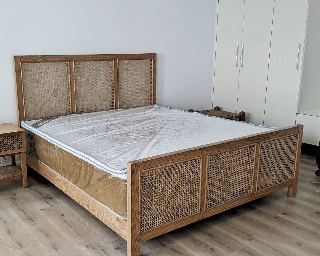 A bed featuring a cane headboard and footboard, adding a touch of natural texture and warmth to the bedroom. The woven cane panels provide visual interest and an airy feel, creating a cozy yet refreshing atmosphere.
