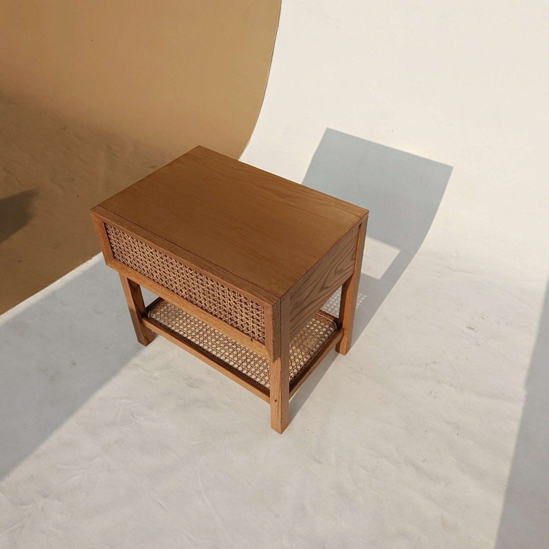  A nightstand with a cane-woven drawer front, offering a stylish storage solution with a touch of natural texture. The woven cane detailing adds visual interest and warmth to the room, while the sleek design ensures functionality and versatility.