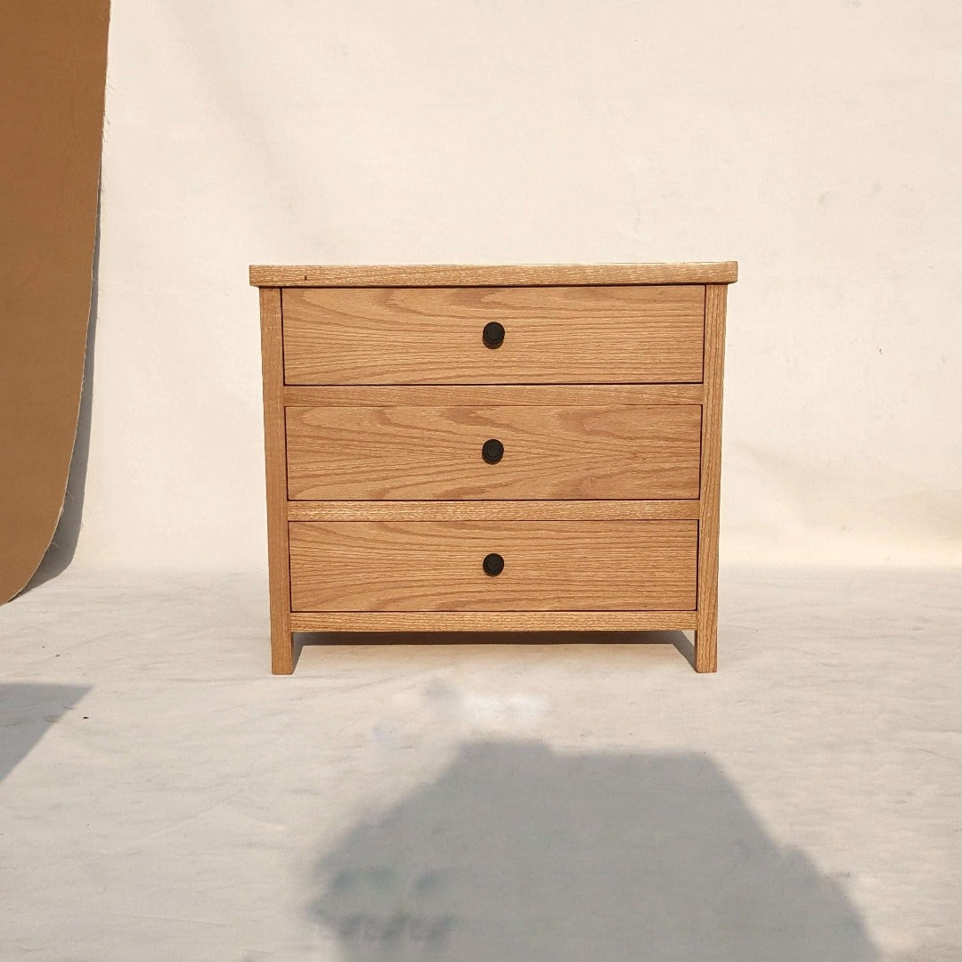 A chunky nightstand, featuring a sturdy and robust design with thick, substantial proportions. Its solid construction and bold silhouette exude a sense of strength and durability, making it a striking and practical addition to any bedroom.