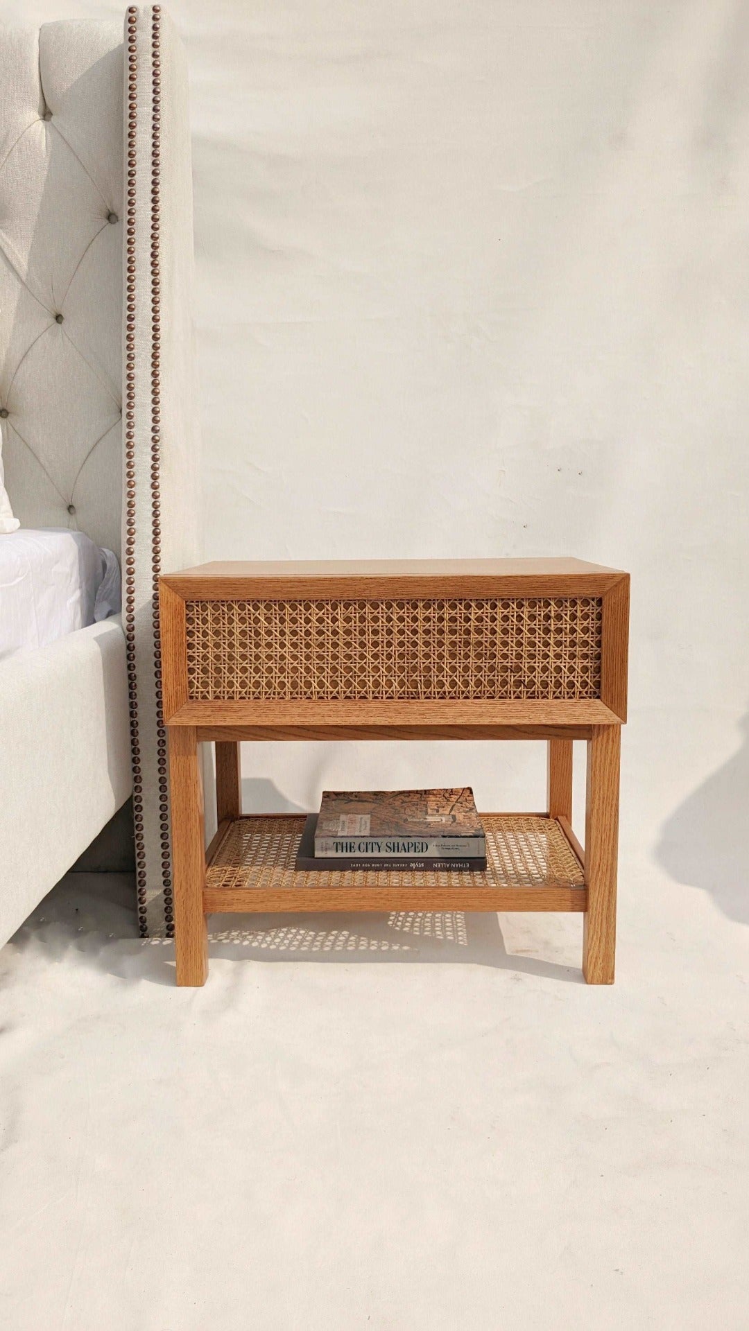  A nightstand with a cane-woven drawer front, offering a stylish storage solution with a touch of natural texture. The woven cane detailing adds visual interest and warmth to the room, while the sleek design ensures functionality and versatility.