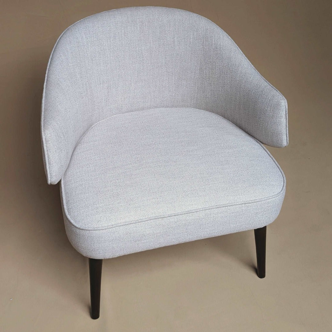 A versatile chair designed for both formal and casual settings, featuring a timeless silhouette and neutral upholstery. Its clean lines and understated design make it suitable for formal dining rooms or relaxed living spaces, offering comfort and style in any environment.