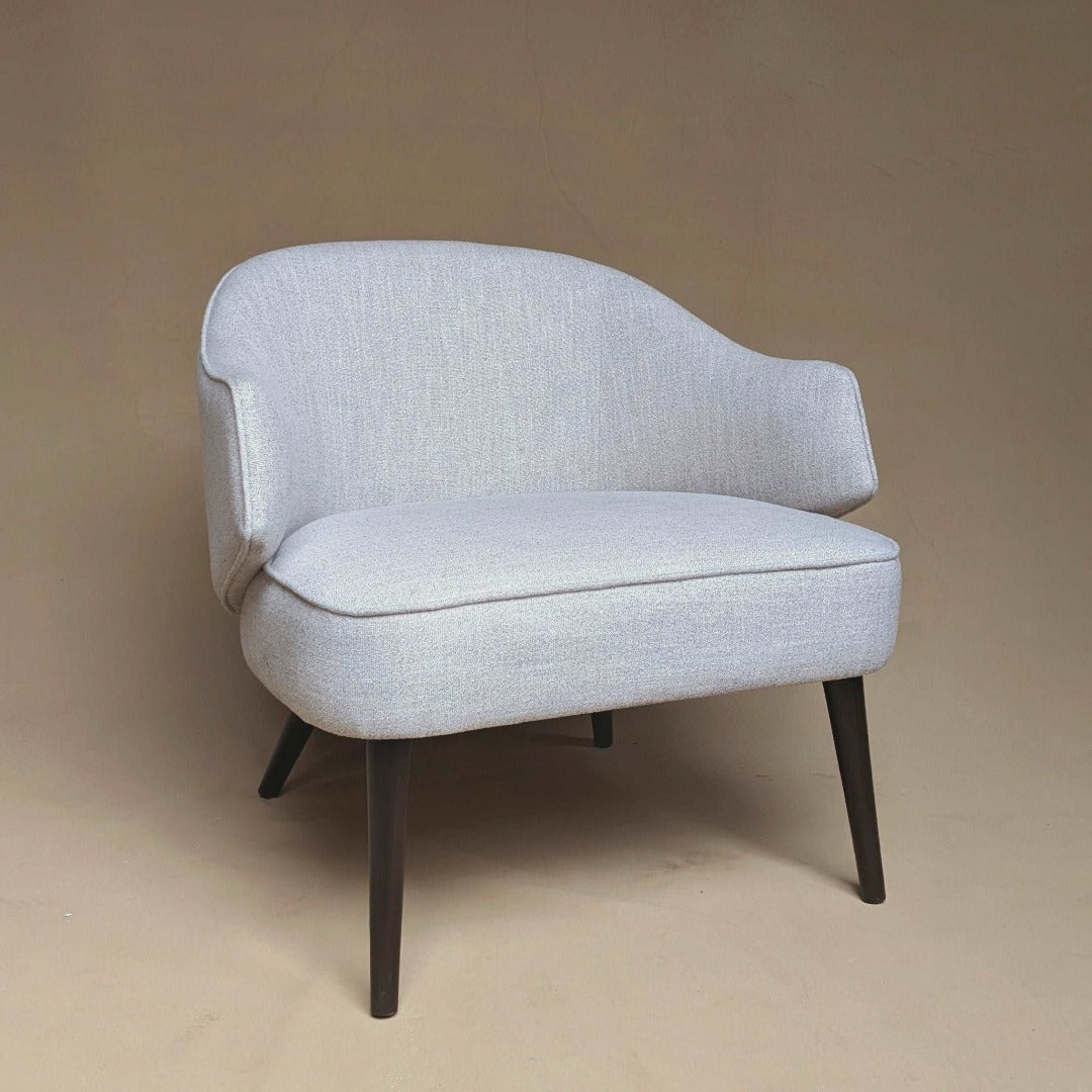 A versatile chair designed for both formal and casual settings, featuring a timeless silhouette and neutral upholstery. Its clean lines and understated design make it suitable for formal dining rooms or relaxed living spaces, offering comfort and style in any environment.
