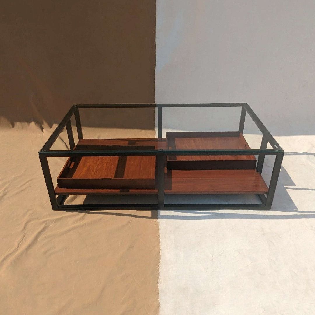 A coffee table featuring a steel frame and a tempered glass top, combining modern aesthetics with durability. The sleek steel frame provides sturdy support, while the tempered glass surface adds a touch of elegance and transparency, creating a contemporary centerpiece for any living room.